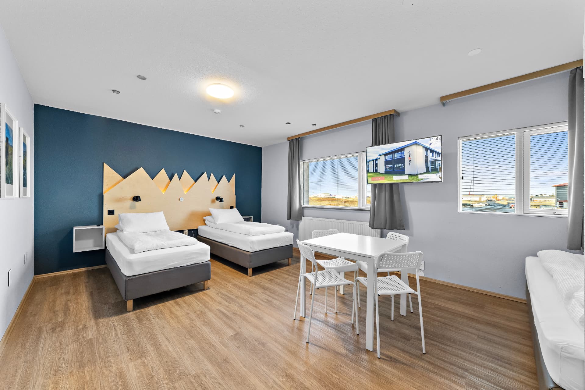Family room with two single beds, mountain headboard, dining table and sofa bed at START Hostel