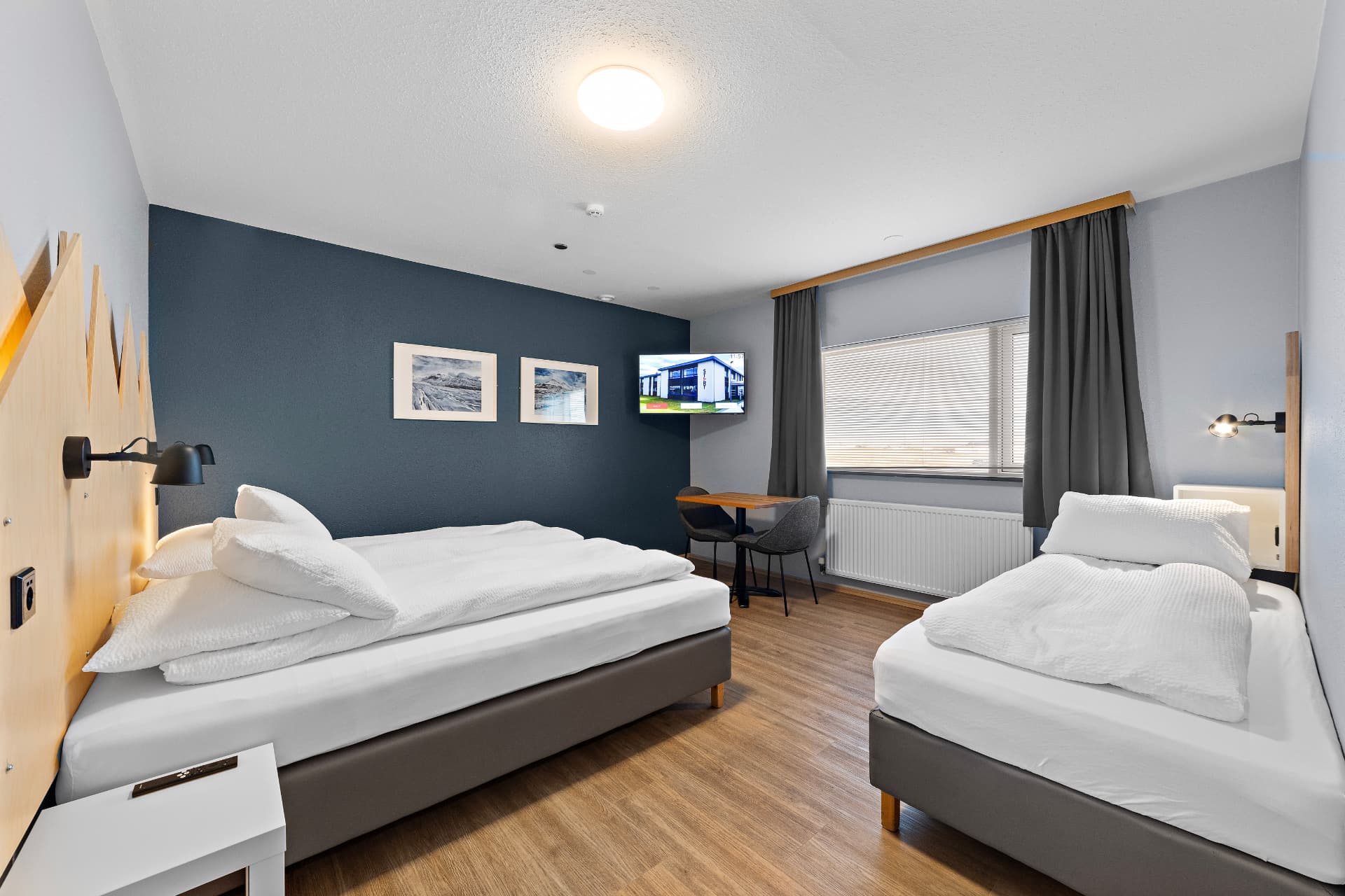 Triple room with private bathroom — double bed and single bed with mountain headboard and dining table at START Hostel