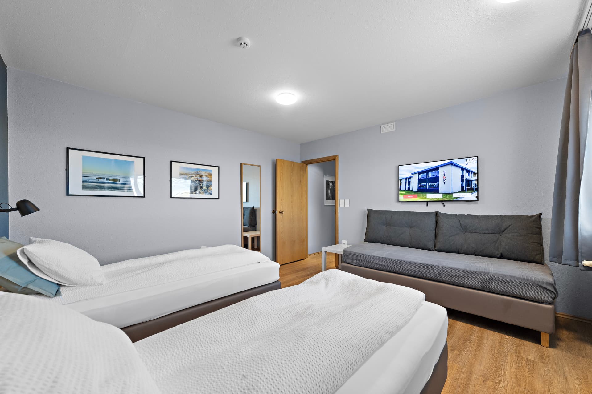 Family room with beds, sofa bed and wall-mounted TV at START Hostel