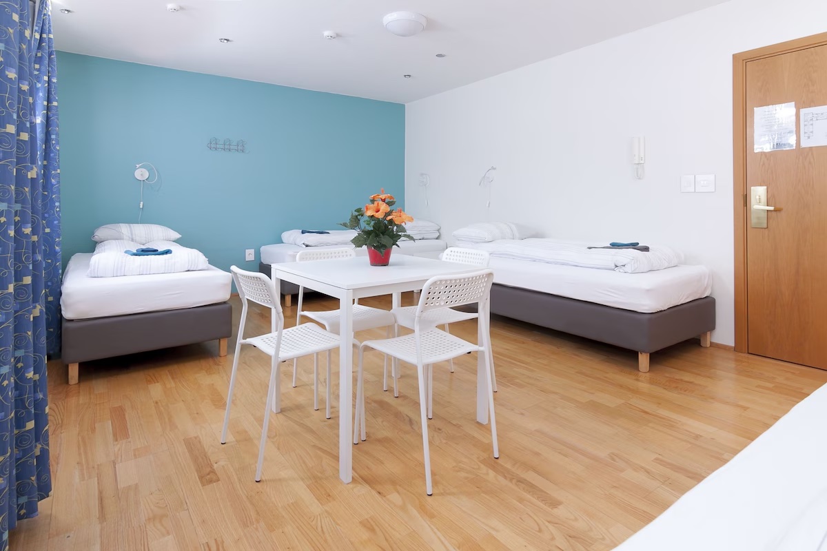 4-bed female dormitory room with single beds, dining table and bright windows at START Hostel