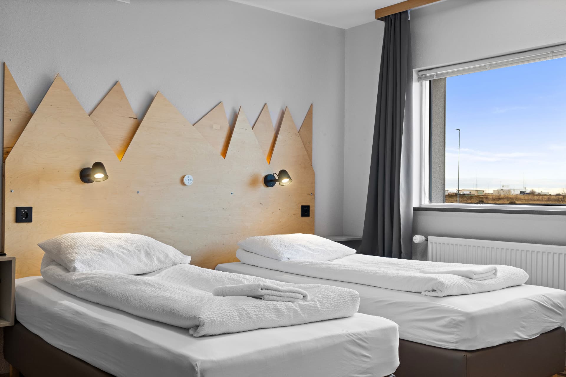 Twin room with private bathroom — two single beds with fresh towels and window view at START Hostel