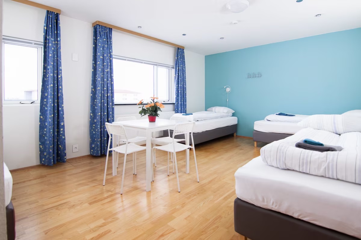 4-bed male dormitory room with single beds, dining table and bright windows at START Hostel
