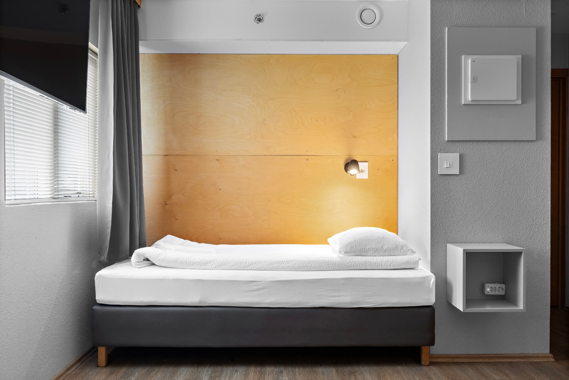 Triple room with shared bathroom — single bed and wooden headboard at START Hostel