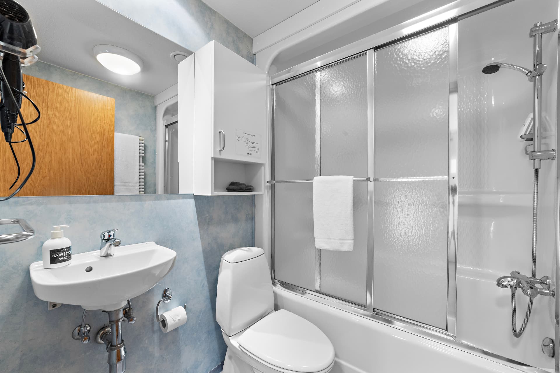 Private bathroom with shower over bath and towels at START Hostel